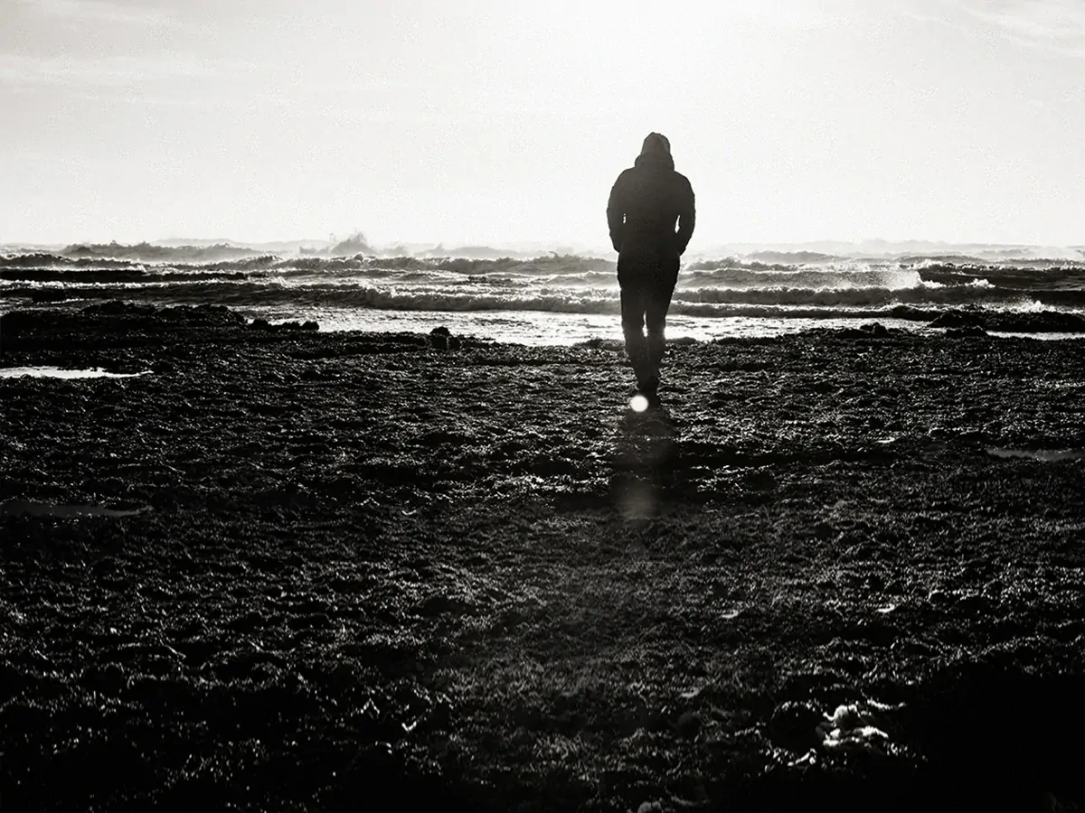 Silhouette-man-zwart-wit Silhouette van een lopende man tegen een zwart-witte achtergrond van zand en golven.