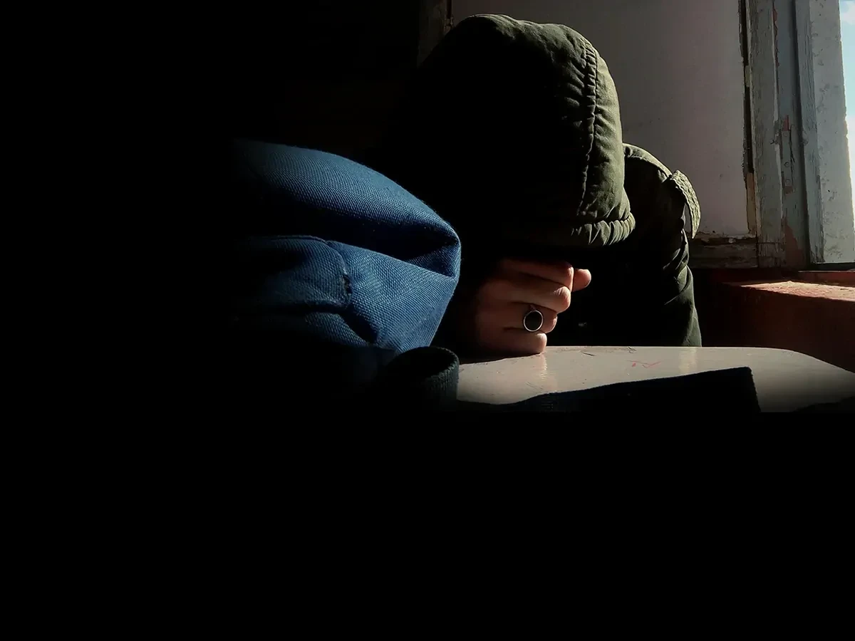 depressieve-persoon-met-hoofd-op-tafel Iemand met een groene capuchon lijkt coke te snuiven en een cocaïneverslaving te hebben.