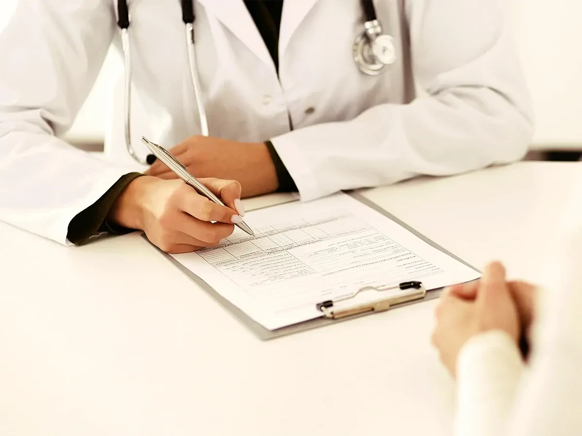 Medisch rapport ligt op tafel en arts in witte jas vult deze in met zilveren pen.