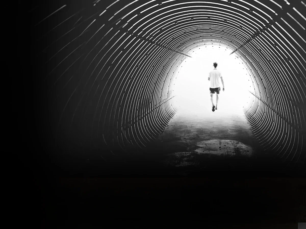 Zwart-wit foto van een man in korte broek en wit t-shirt lopend door een tunnel. 