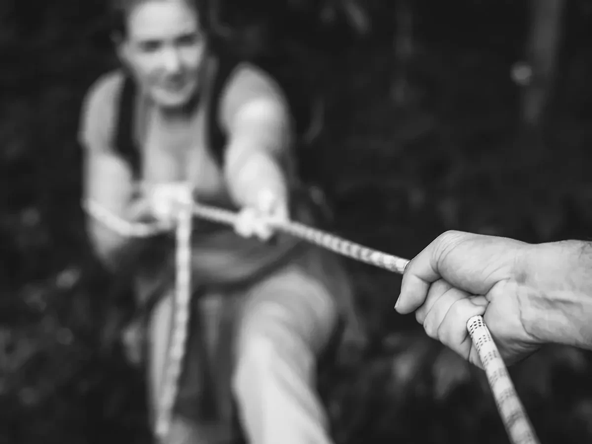 Zwart-wit foto van twee mensen die aan een touw trekken.